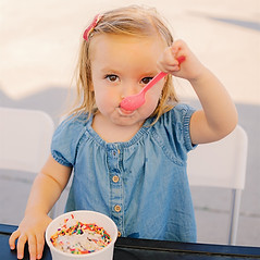 A toddler eating a cup of sprinkle-topped ice cream