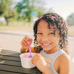 A smiling girl with a cup of ice cream at an outdoor event