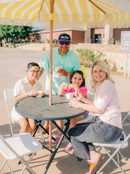 A family enjoying ice cream at a table under a striped umbrella